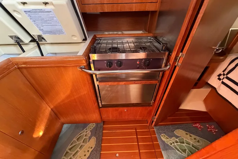 Slide: The Image of Compact kitchen area in a 2002 Hunter 356 sailboat with a stove and wooden cabinetry. - 29