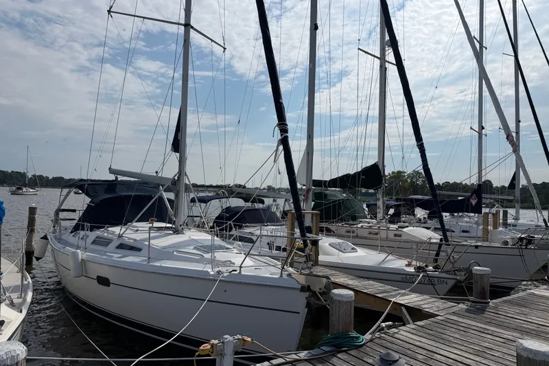 The Image of Sailboats docked at a marina, featuring a 2002 Hunter 356 model under a partly cloudy sky. - 1
