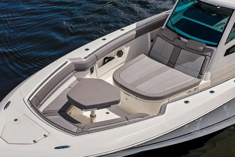 Slide: The Image of 2023 Boston Whaler 380 Outrage boat interior with cushioned seating and table on water. - 6
