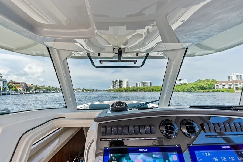 Slide: The Image of 2023 Boston Whaler 380 Outrage helm view with modern navigation system on a scenic waterway. - 31