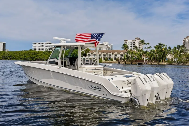 Slide: The Image of 2023 Boston Whaler 380 Outrage boat on water, American flag, coastal background. - 16