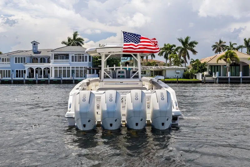 Slide: The Image of 2023 Boston Whaler 380 Outrage with quad engines, American flag, waterfront homes in background. - 13