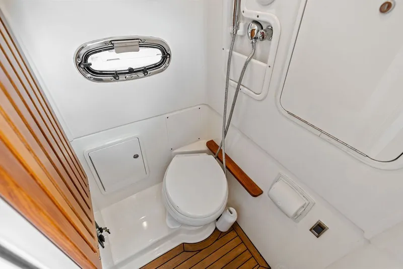 Slide: The Image of 2023 Boston Whaler 380 Outrage bathroom with wooden accents and compact design. - 57