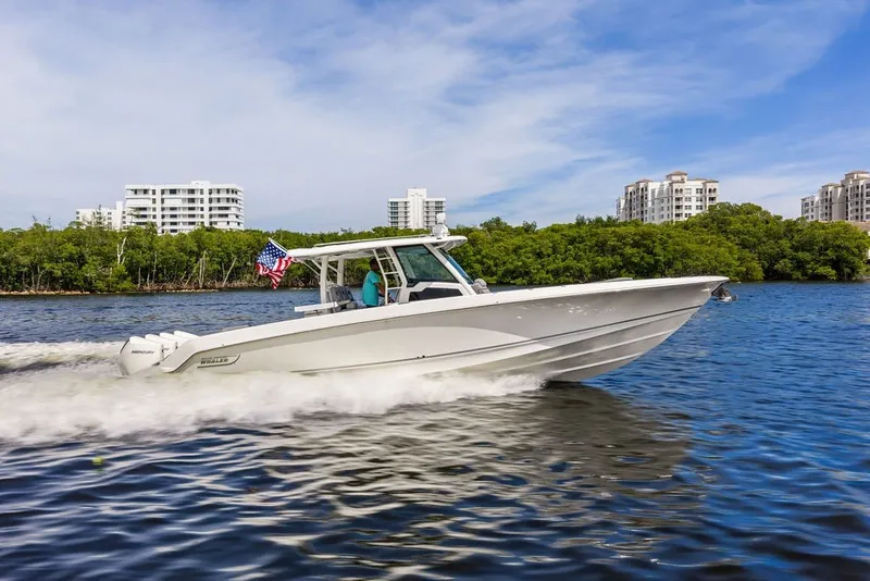 Slide: The Image of 2023 Boston Whaler 380 Outrage cruising on water with cityscape background. - 10