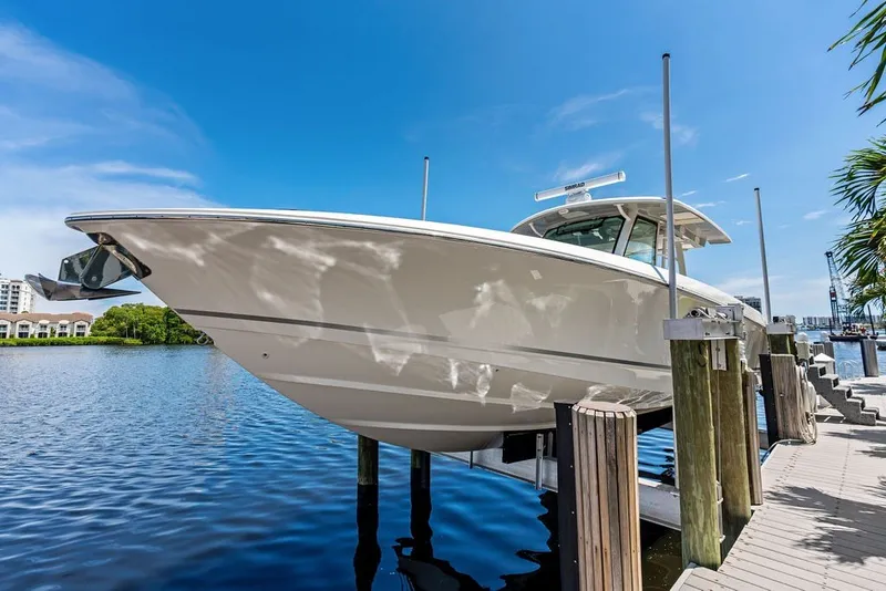 Slide: The Image of 2023 Boston Whaler 380 Outrage boat docked by the waterfront under a clear blue sky. - 21