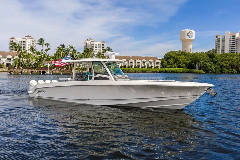 Slide: The Image of 2023 Boston Whaler 380 Outrage cruising on a scenic waterway with buildings in the background. - 11