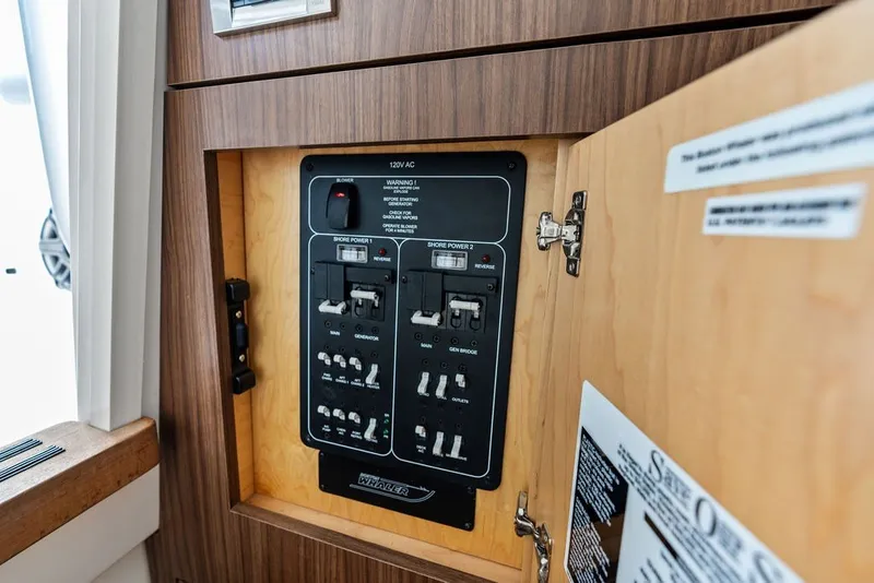 Slide: The Image of Electrical panel inside 2023 Boston Whaler 380 Outrage, showcasing circuit breakers and controls. - 60