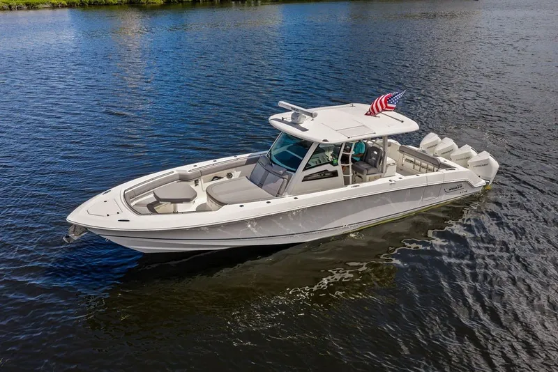 Slide: The Image of 2023 Boston Whaler 380 Outrage boat cruising on calm water with American flag. - 4