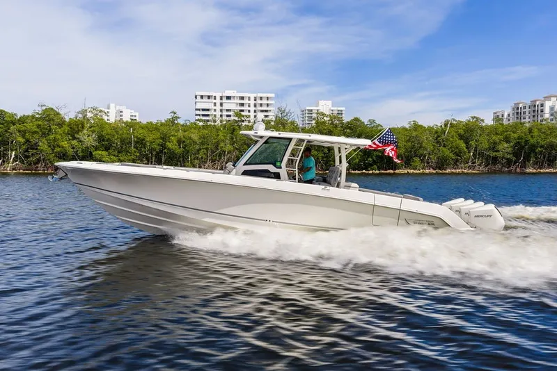 Slide: The Image of 2023 Boston Whaler 380 Outrage cruising on water with American flag, cityscape background. - 15