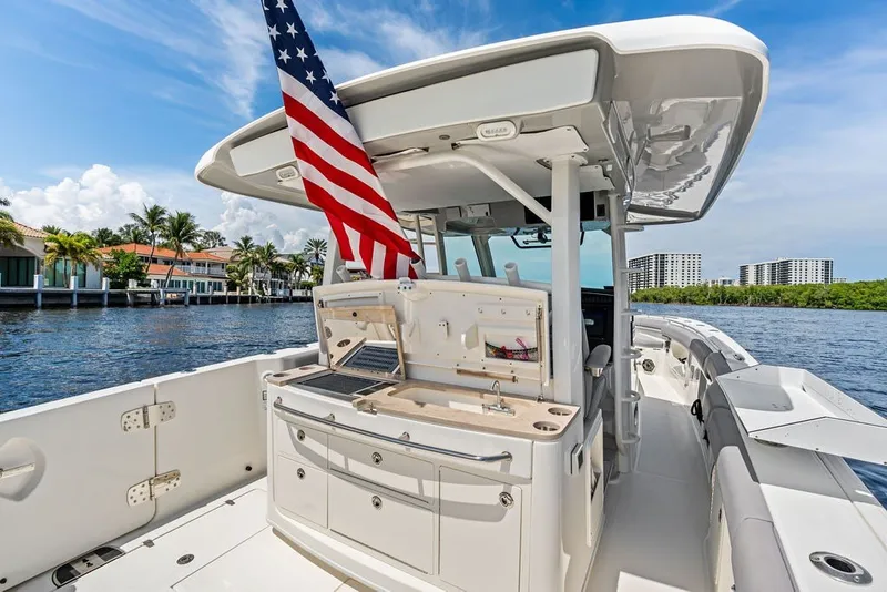 Slide: The Image of 2023 Boston Whaler 380 Outrage boat with American flag, docked near waterfront homes. - 40