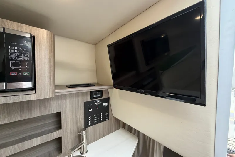 Slide: The Image of 2021 Regal 26 Express interior with TV, microwave, and control panel. - 29