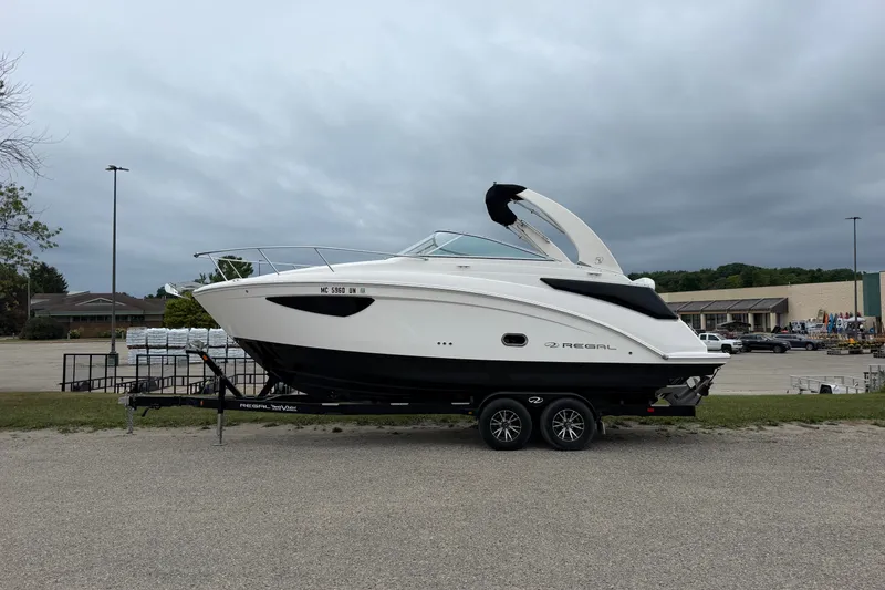 The Image of 2021 Regal 26 Express boat on trailer in parking lot, overcast sky. - 0