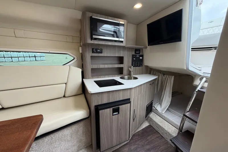 Slide: The Image of Interior of 2021 Regal 26 Express boat featuring kitchenette, seating, and modern amenities. - 31
