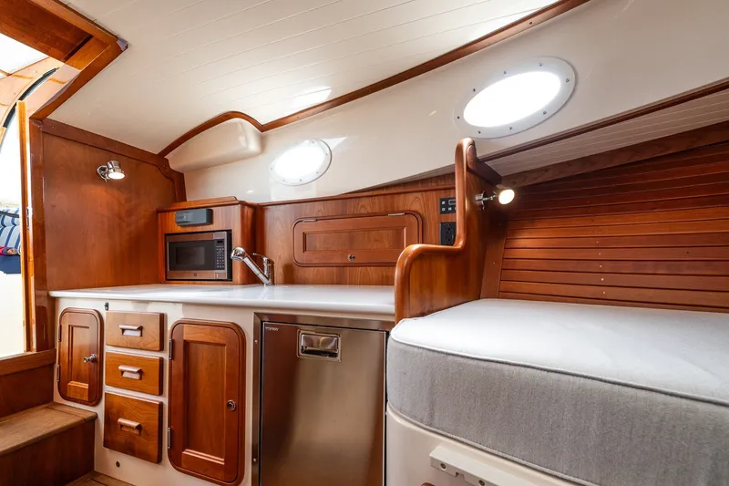 Slide: The Image of 2018 Hinckley Picnic Boat 34 MKII interior with wood cabinetry, microwave, and seating. - 27