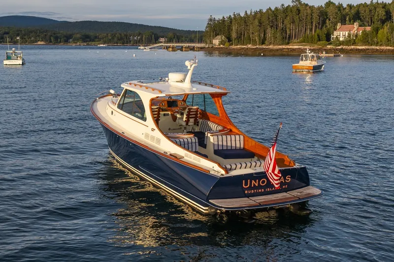 Slide: The Image of 2018 Hinckley Picnic Boat 34 MKII cruising on serene waters near a wooded shoreline. - 2