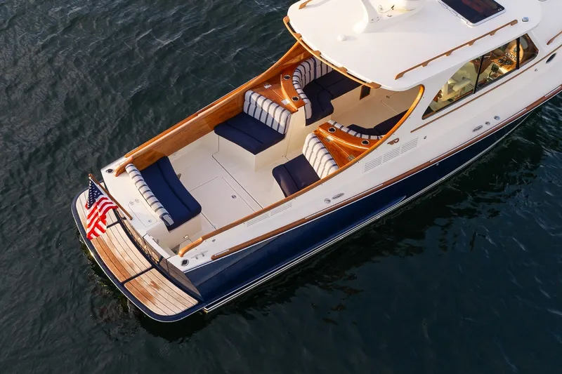 Slide: The Image of 2018 Hinckley Picnic Boat 34 MKII on water, featuring elegant seating and American flag. - 11