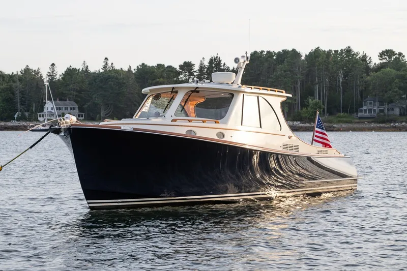 The Image of 2018 Hinckley Picnic Boat 34 MKII on serene water, with forested shoreline backdrop. - 0