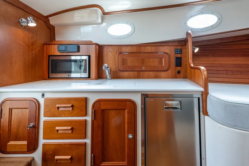 Slide: The Image of 2018 Hinckley Picnic Boat 34 MKII interior with wood cabinetry, microwave, and stainless steel fridge. - 28