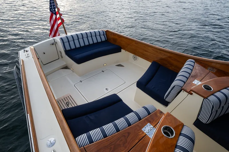 Slide: The Image of 2018 Hinckley Picnic Boat 34 MKII with elegant seating and American flag on calm water. - 9