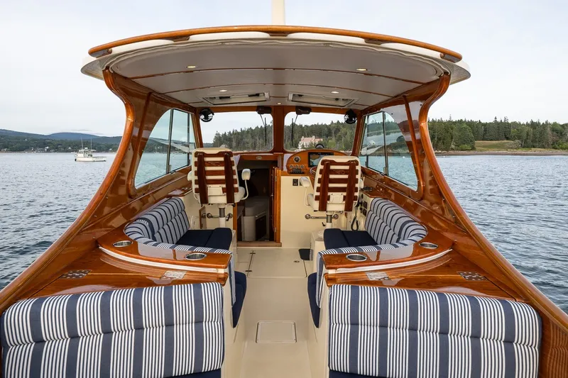 Slide: The Image of 2018 Hinckley Picnic Boat 34 MKII interior with striped seating, elegant wood finish, and scenic water view. - 15
