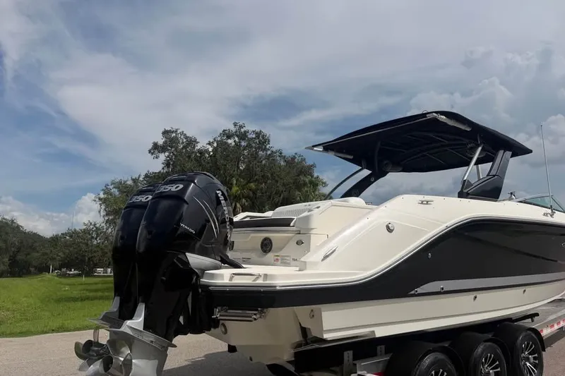 Slide: The Image of 2019 Sea Ray SLX 310 Outboard boat with dual engines on a trailer, under a cloudy sky. - 7