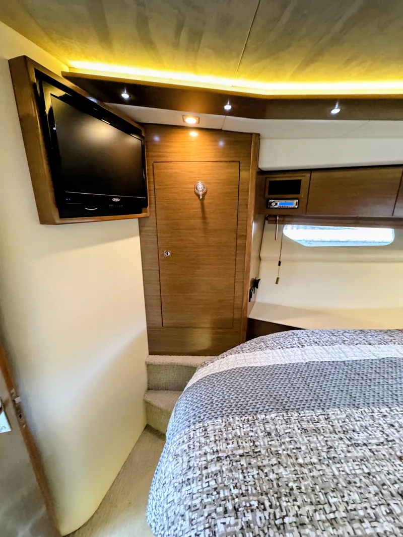 Slide: The Image of Interior of the 2016 Cruisers Yachts 45 Cantius with cozy bed, TV, and wood paneling. - 36