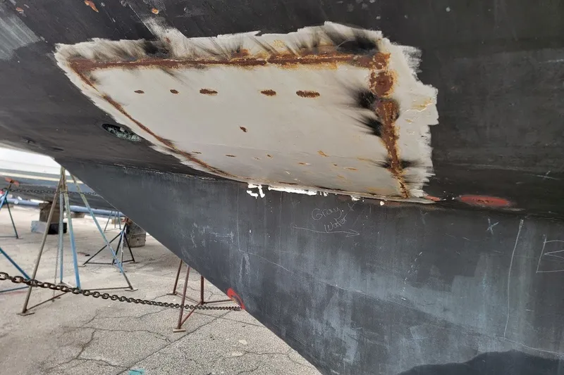 Slide: The Image of Hull repair on 1989 Custom Rob Ladd PH Motorsailer Cutter, showing patchwork and rust. - 79