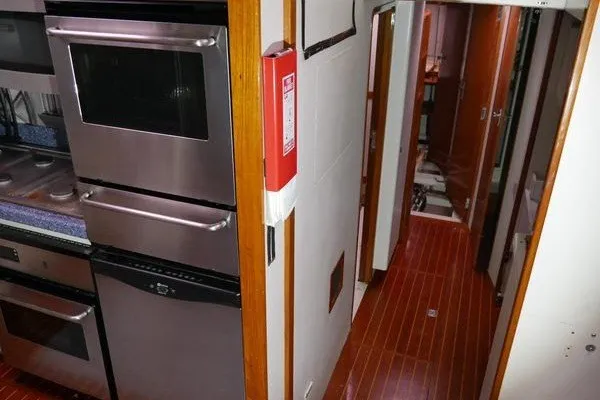 Slide: The Image of Interior of 1989 Custom Robb Ladd Pilothouse Cutter, featuring kitchen appliances and wooden flooring. - 18