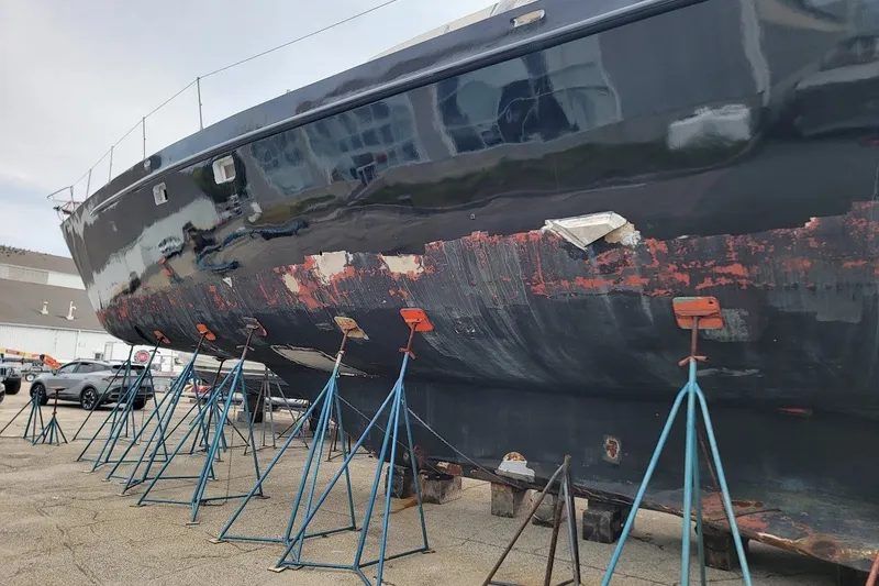 Slide: The Image of 1989 Custom Rob Ladd PH Motorsailer Cutter on stands, showing hull wear and restoration needs. - 70