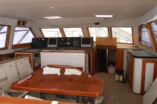 Slide: The Image of Interior of a sailboat with wooden table, helm station, and large windows. - 2