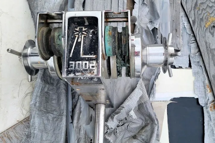 Slide: The Image of Winch mechanism on 1989 Custom Rob Ladd PH Motorsailer Cutter, surrounded by weathered materials. - 49