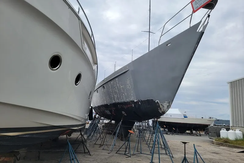 Slide: The Image of Two boats on stands, including a 1989 Custom Rob Ladd PH Motorsailer Cutter, in a shipyard. - 73