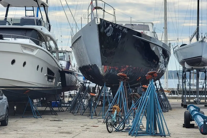 Slide: The Image of Boats in a marina, including a 1989 Custom Rob Ladd PH Motorsailer Cutter, on stands. - 2