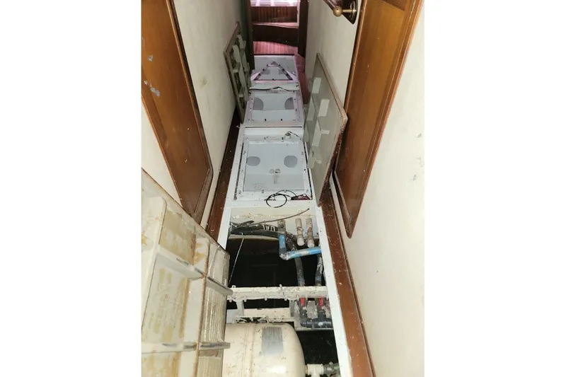 Slide: The Image of Narrow corridor with open floor panels revealing pipes on a 1989 Custom Robb Ladd Pilothouse Cutter. - 22