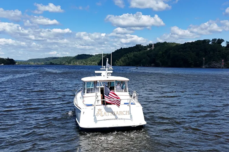 Slide: The Image of Alden 40 Express 1999 boat cruising on a scenic river under a blue sky. - 3