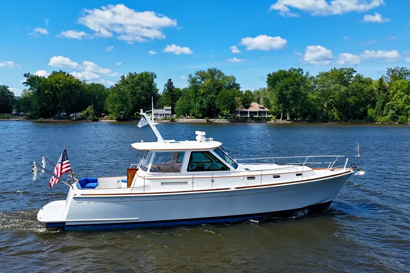 Slide: The Image of Alden 40 Express 1999 yacht cruising on a scenic lake under a clear blue sky. - 2