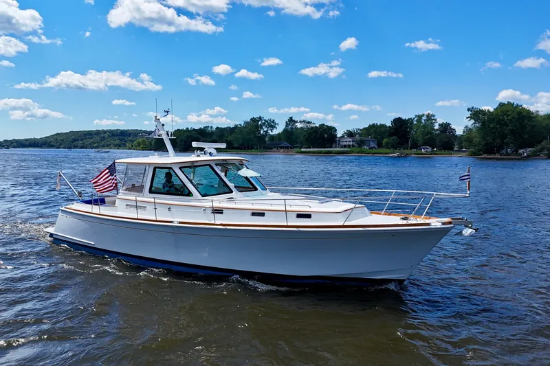 Slide: The Image of Alden 40 Express 1999 cruising on a sunny day with scenic shoreline backdrop. - 1