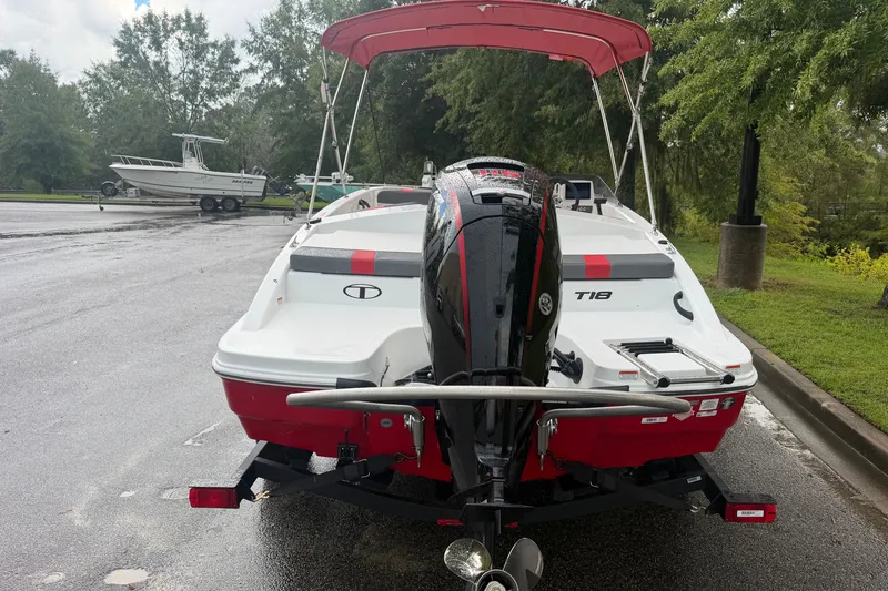 Slide: The Image of 2027 Tahoe T18 boat with outboard motor, parked on a wet surface, surrounded by trees. - 3