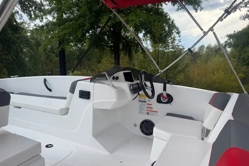 Slide: The Image of 2027 Tahoe T18 boat interior with steering wheel, seating, and canopy, surrounded by trees. - 4