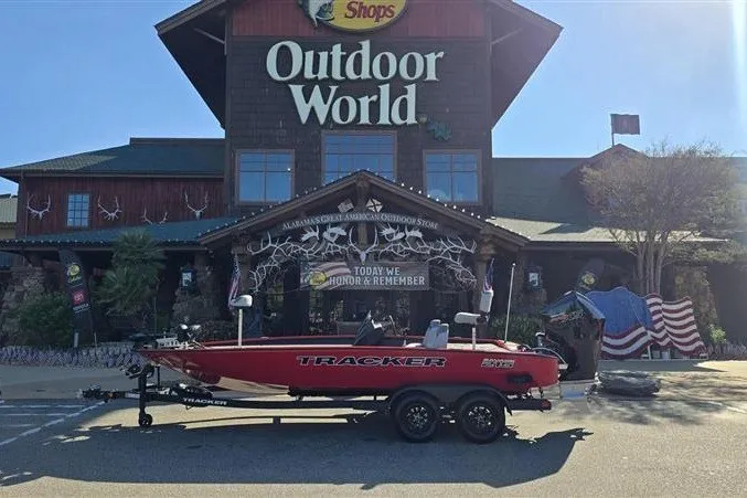 The Image of Red 2027 Tracker Savage 215 boat on trailer outside Outdoor World store. - 0