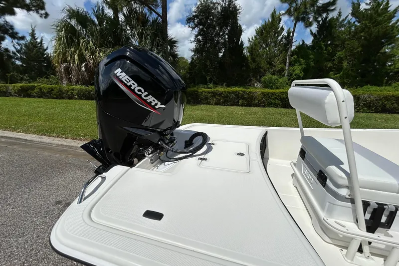 Slide: The Image of 2027 Mako Pro Skiff 17 CC with Mercury outboard motor, white seating, and lush greenery background. - 7
