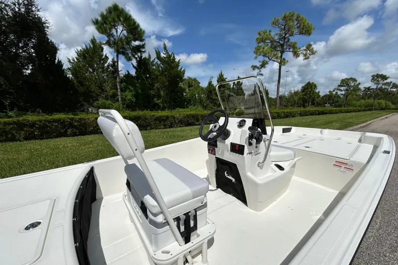Slide: The Image of 2027 Mako Pro Skiff 17 CC boat interior with steering console and seating, set against a lush landscape. - 8