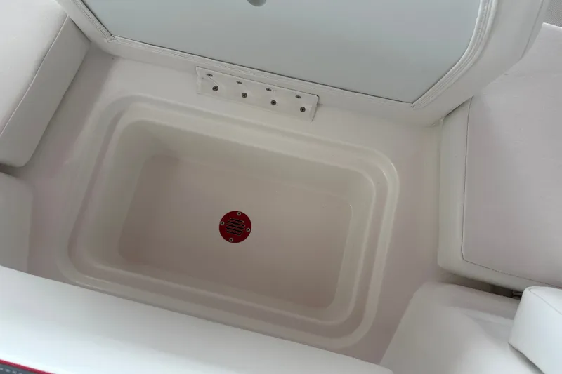 Slide: The Image of 2027 Tahoe T18 boat storage compartment with white interior and red drain plug. - 20