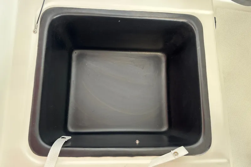 Slide: The Image of Storage compartment in a 2027 Tahoe T18 boat, featuring a black interior and white strap. - 27