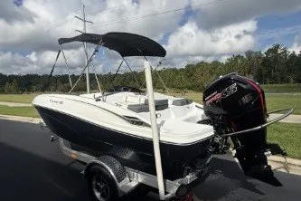 Slide: The Image of 2027 Tahoe T18 boat on trailer with outboard motor, parked outdoors. - 2