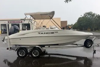Slide: The Image of 2027 Tahoe 1950 boat on trailer in parking lot, overcast day. - 2