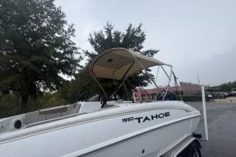Slide: The Image of 2027 Tahoe 1950 boat with canopy on trailer, parked outdoors. - 7