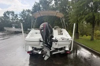 Slide: The Image of 2027 Tahoe 1950 boat on trailer, parked on wet road with trees in background. - 4
