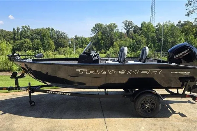 The Image of 2027 Tracker Pro Guide V-16 SC boat on trailer, parked outdoors. - 0