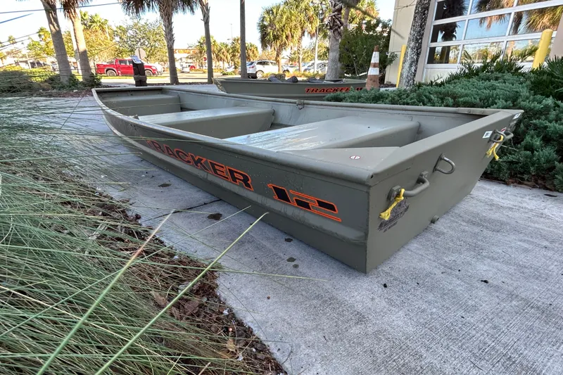 The Image of 2027 Tracker Grizzly 12 Jon boat on concrete path, surrounded by greenery. - 0